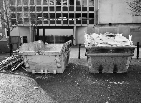 Pile of household waste next to a skip in a residential area
